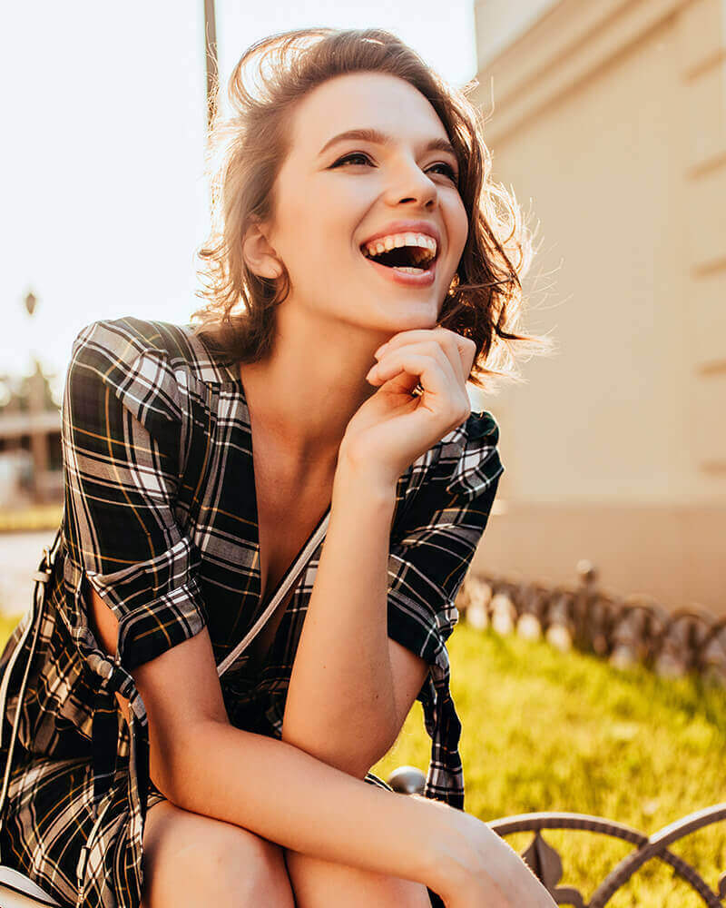 woman sitting on fence haughing