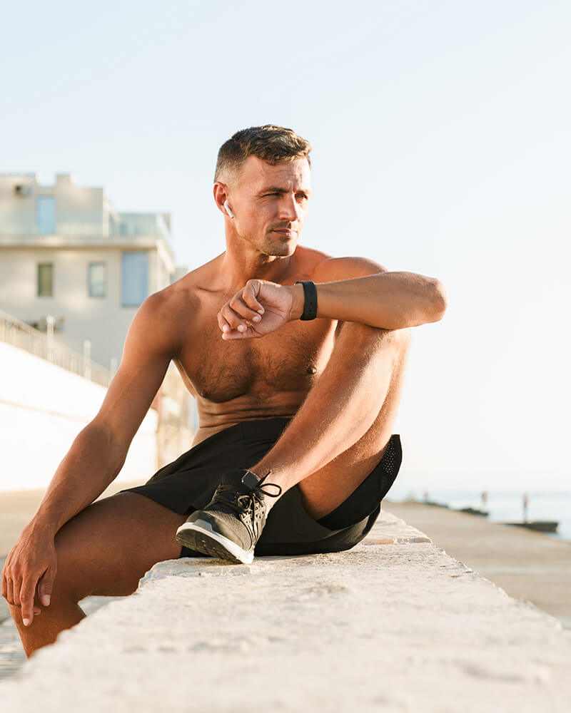 Fit man sitting an a wall